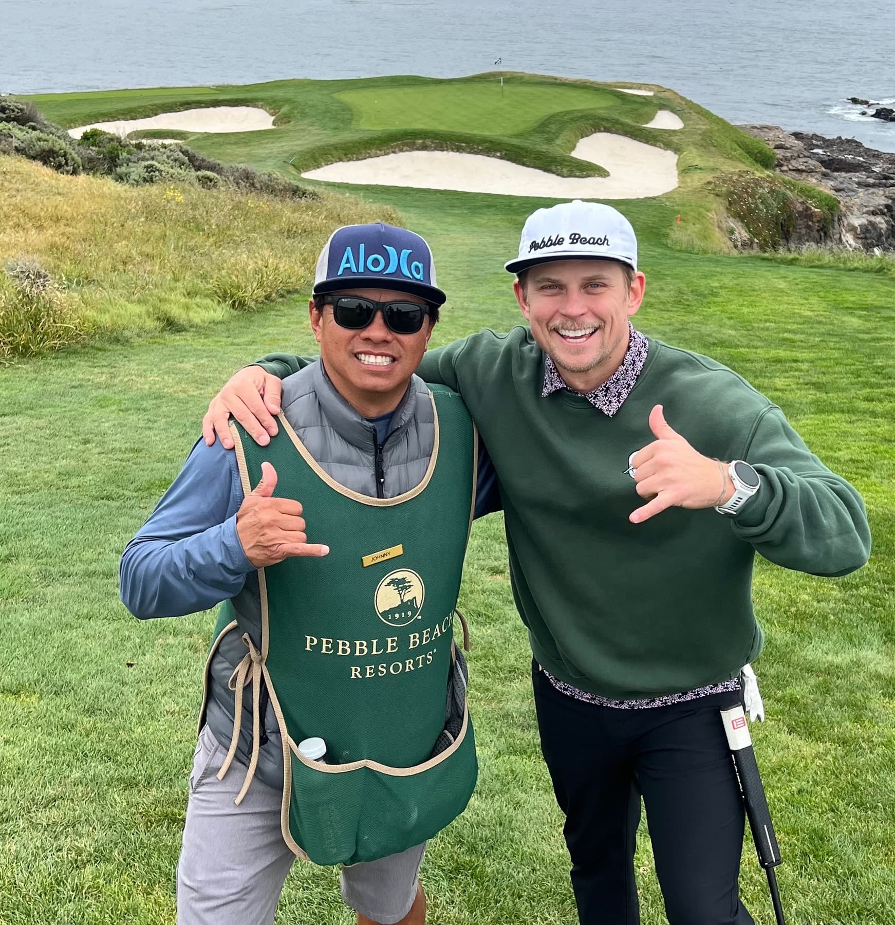 Johnny and a golfer giving shakas above a green by the sea