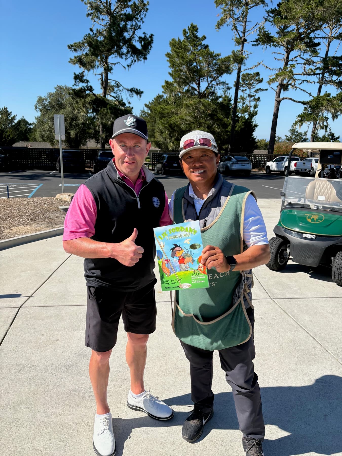 Johnny and a golfer holding the book by the carts