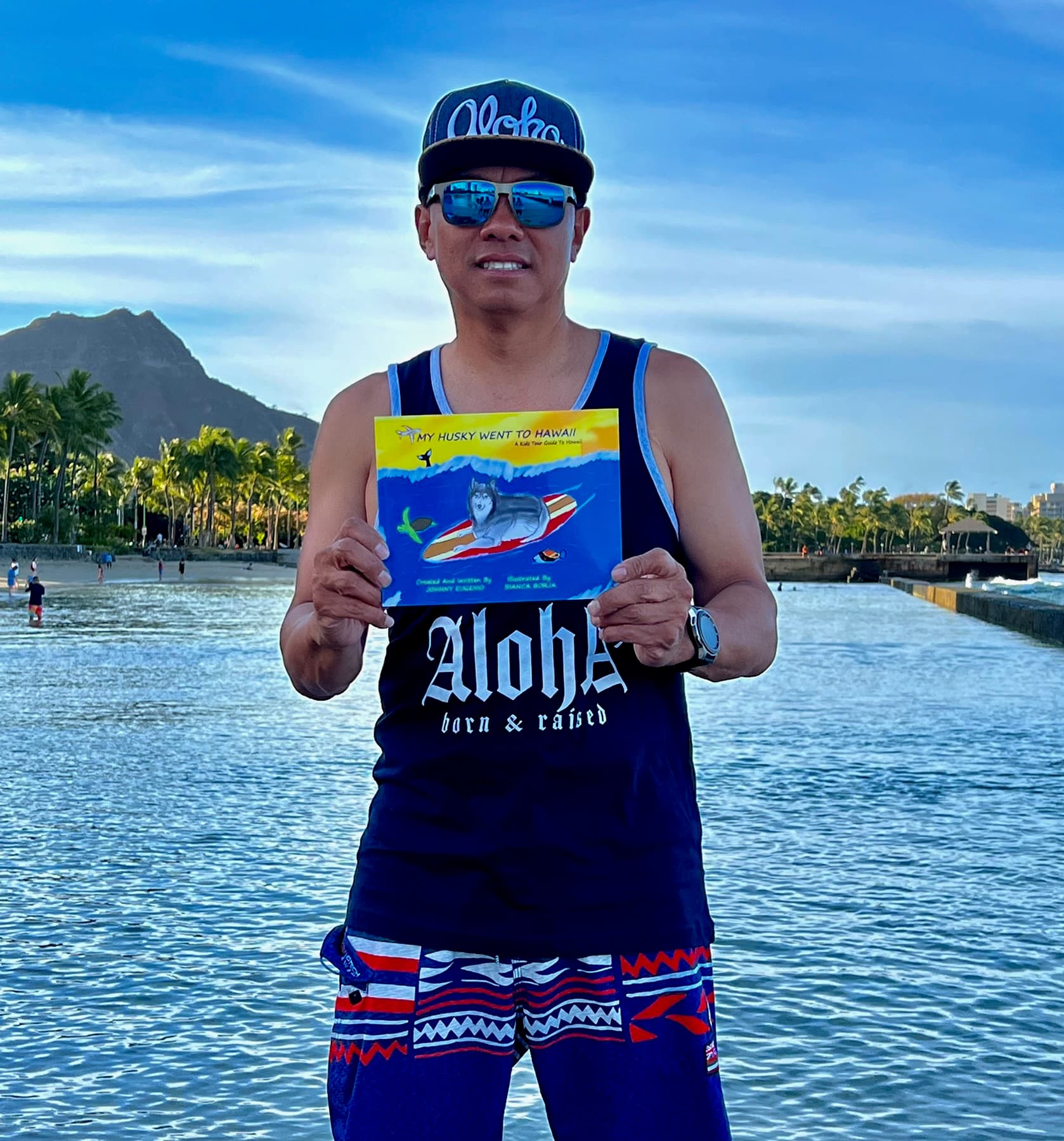 Johnny holding his book My Husky Went To Hawaii by the water in Hawaii