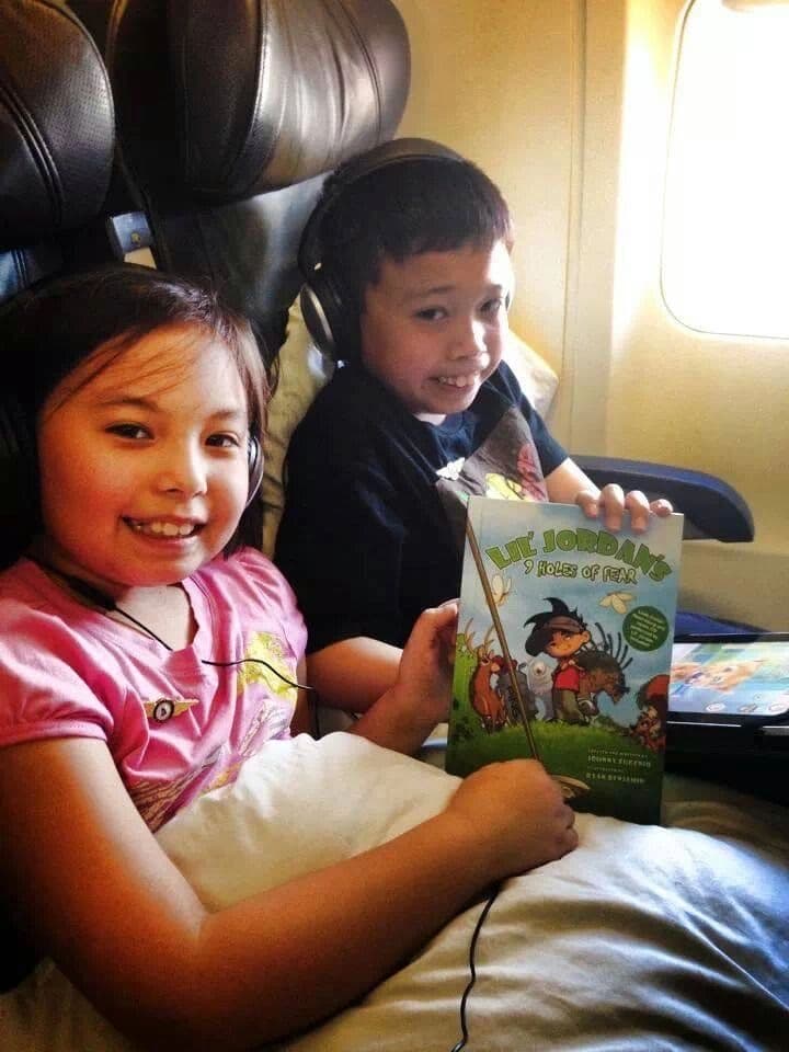 Two children reading the book on a plane