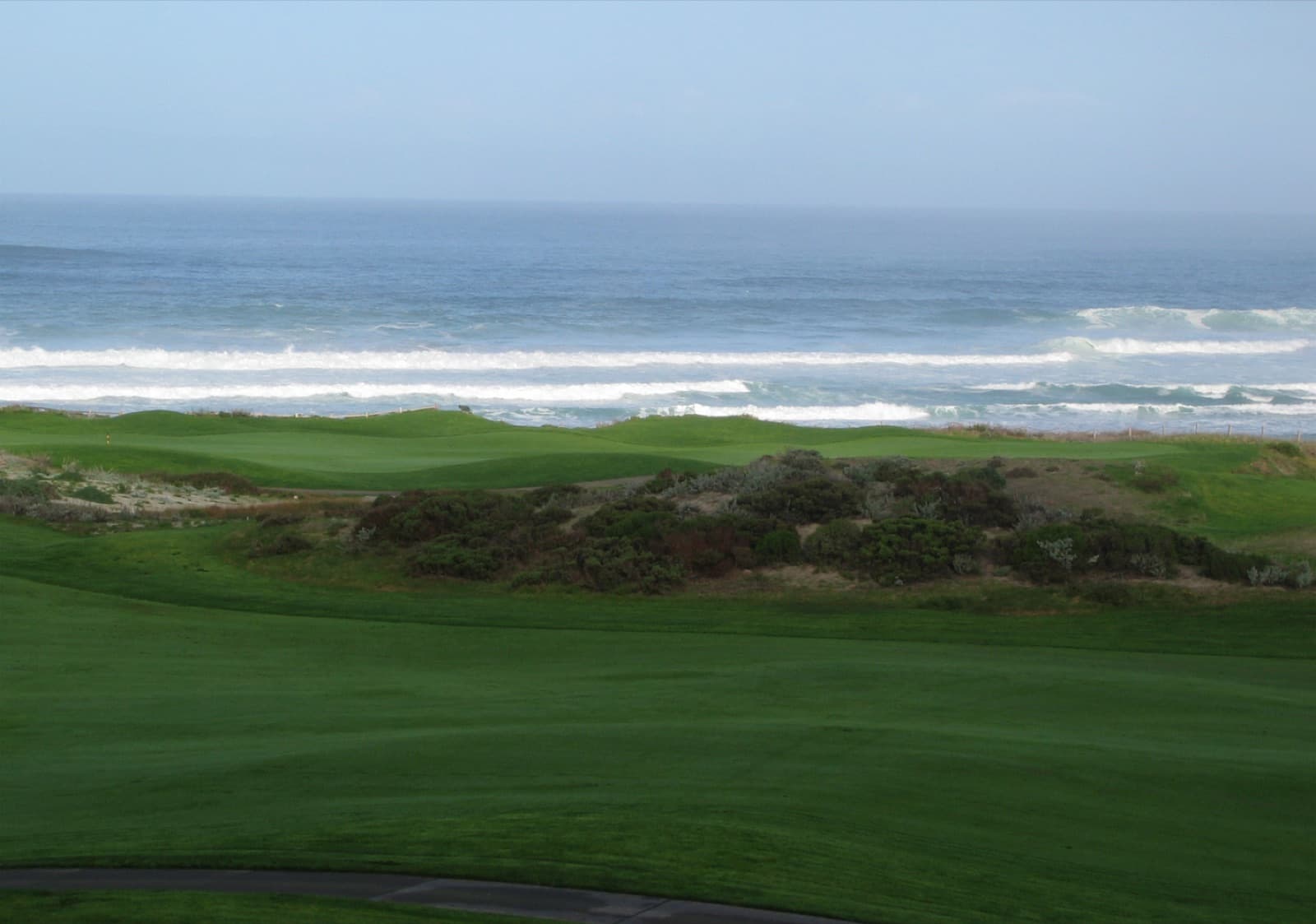 The Pacific Ocean beyond the dunes and the first fairway at The Links at Spanish Bay