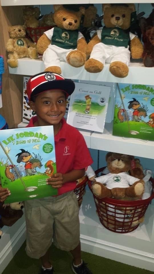 A young golfer holding the book